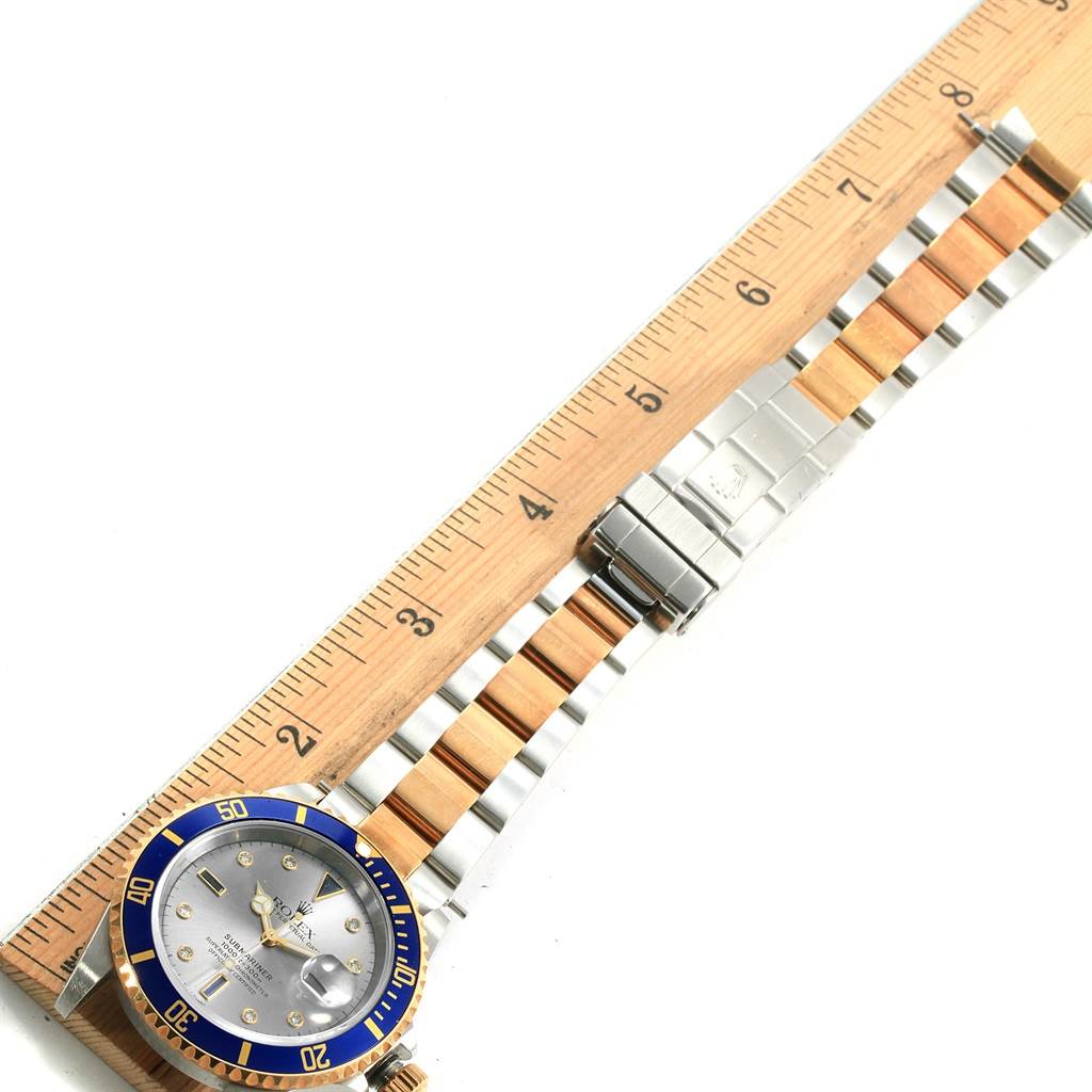 The image shows a Rolex Submariner 16613 Men's Steel and Gold (two tone) Grey Dial 16613 Men's Steel and Gold (two tone) Grey Dial watch laid flat next to a measuring ruler, displaying the face and two-tone bracelet.
