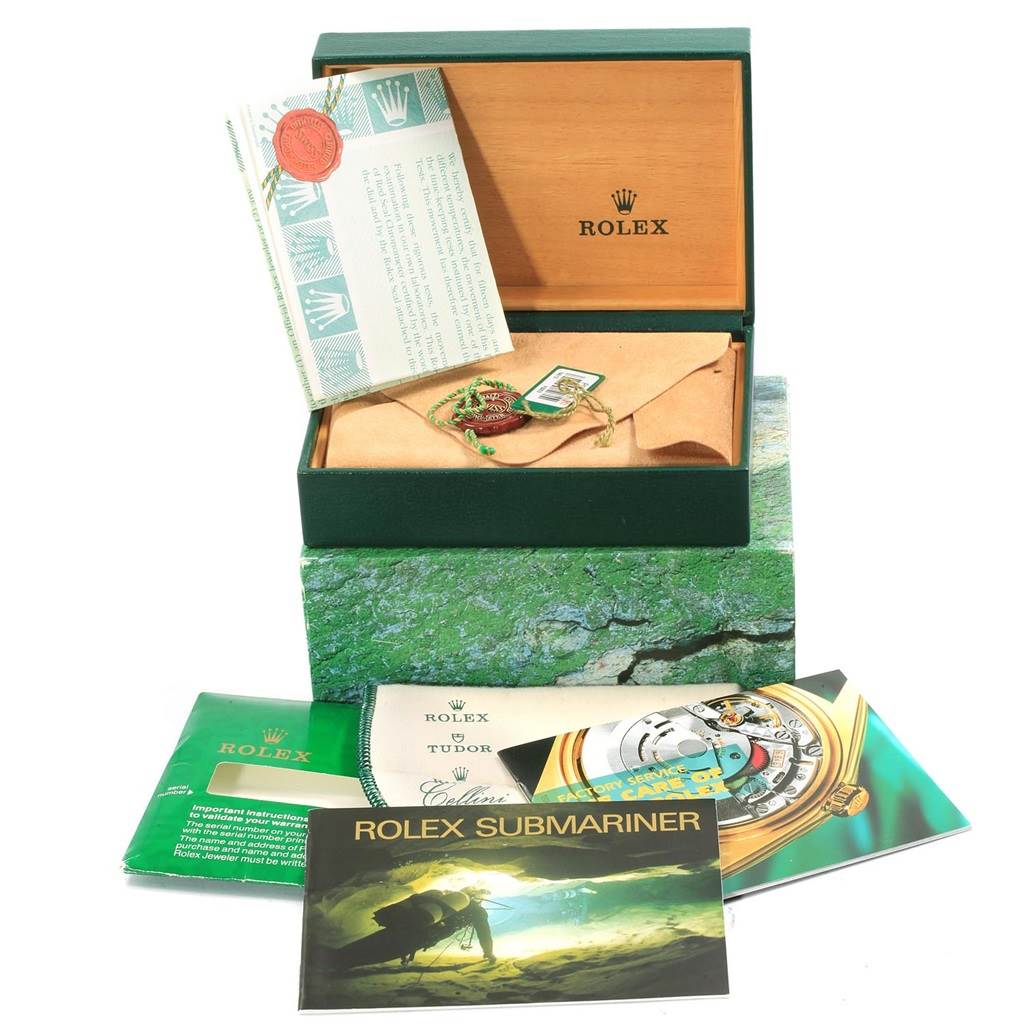 This image shows the open box and manuals for a Rolex Submariner 16613 Men's Steel and Gold (two tone) Champagne Dial 16613 Men's Steel and Gold (two tone) Champagne Dial watch, including a tag and booklets.