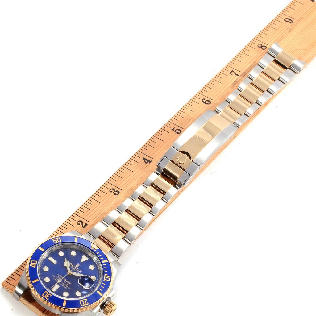 The image shows a Rolex Submariner 116613 Men's Steel and Gold (two tone) Blue Dial 116613 Men's Steel and Gold (two tone) Blue Dial watch laid flat, showcasing the face, bezel, bracelet, and clasp, next to a measuring ruler.