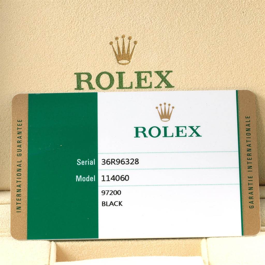 The image shows an international guarantee card for the Rolex Submariner 114060 Men's Stainless Steel Black Dial 114060 Men's Stainless Steel Black Dial model 114060, displayed inside a Rolex box.