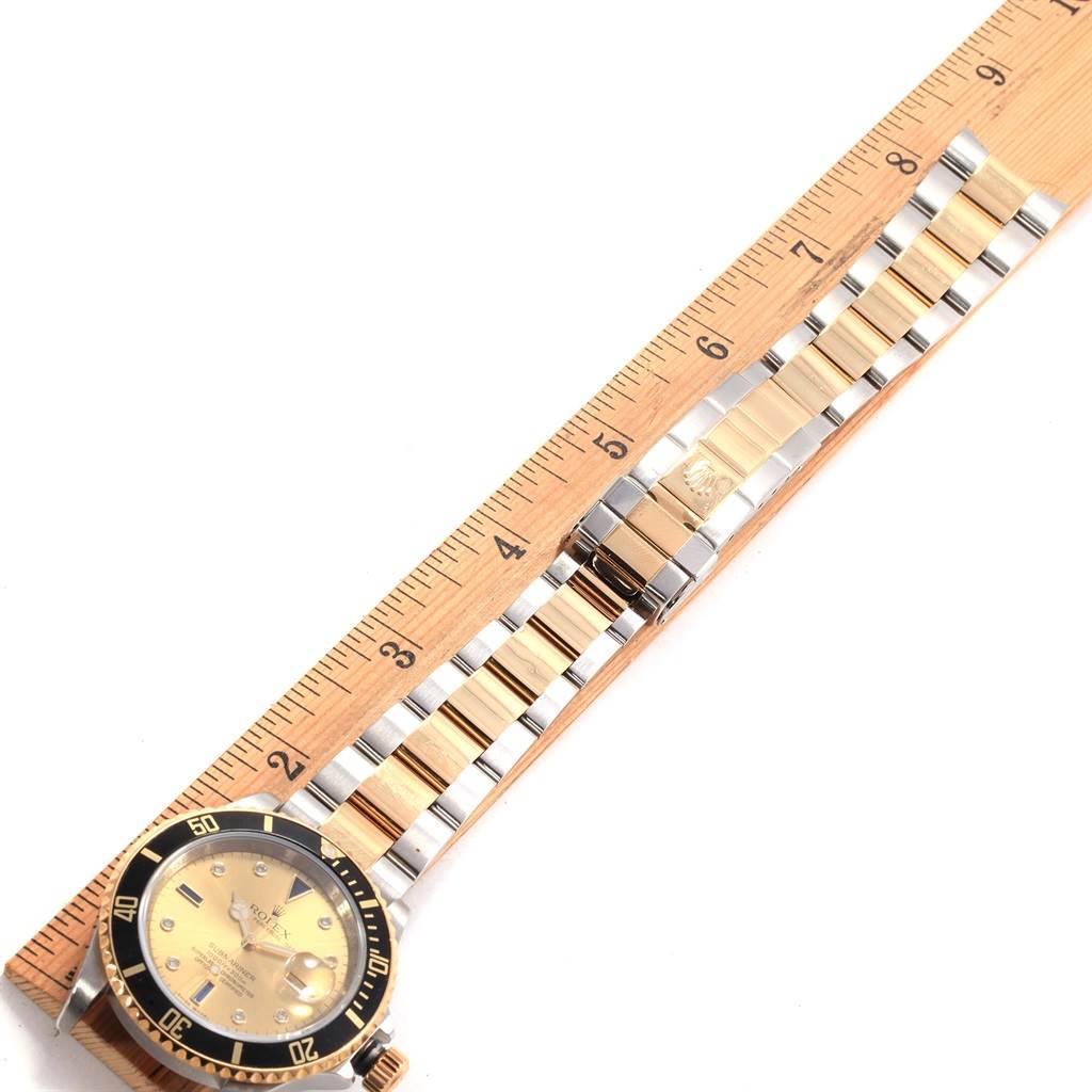 The image shows the face and bracelet of a Rolex Submariner 16613 Men's Steel and Gold (two tone) Champagne Dial 16613 Men's Steel and Gold (two tone) Champagne Dial watch, laid out next to a ruler for measurement.