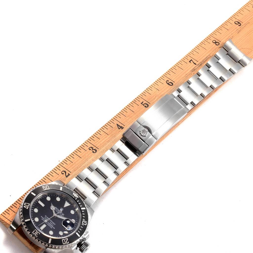 The image shows a top-down view of a Rolex Submariner 116610 Men's Stainless Steel Black Dial 116610 Men's Stainless Steel Black Dial watch, highlighting its face, bezel, and metal bracelet beside a ruler.