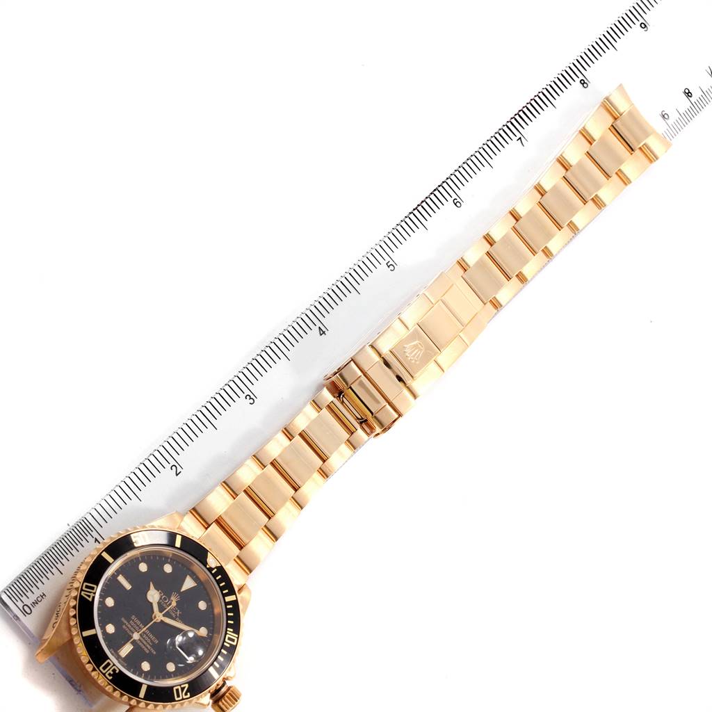 The image shows a full view of the Rolex Submariner 16618 Men's Yellow Gold Black Dial 16618 Men's Yellow Gold Black Dial watch laid flat next to a ruler for scale.