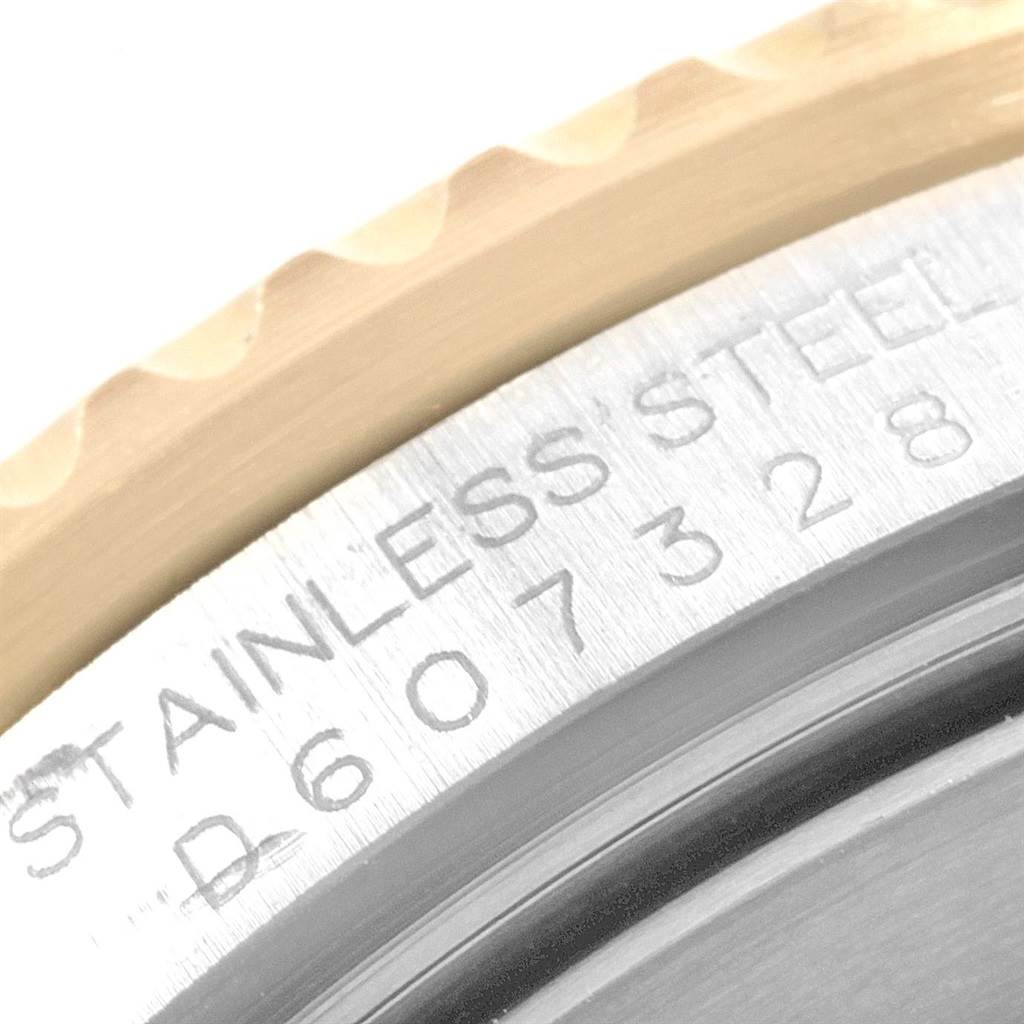 The image shows a close-up of the Rolex Submariner 16613 Men's Steel and Gold (two tone) Grey Dial 16613 Men's Steel and Gold (two tone) Grey Dial's bezel edge, and a portion of the stainless steel case with engravings.