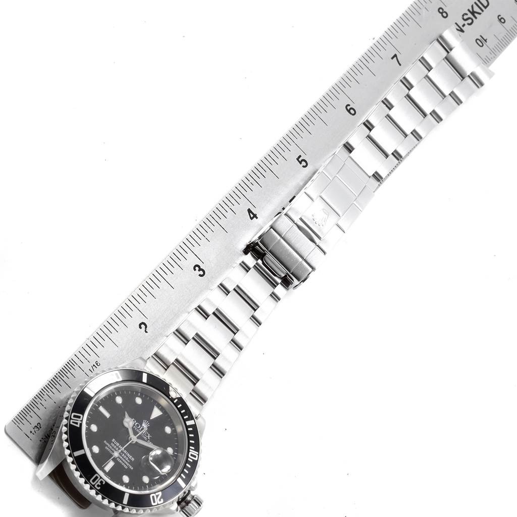 The image shows a Rolex Submariner 16610 Men's Stainless Steel Black Dial 16610 Men's Stainless Steel Black Dial watch lying flat with a metal ruler measuring its stainless steel bracelet.