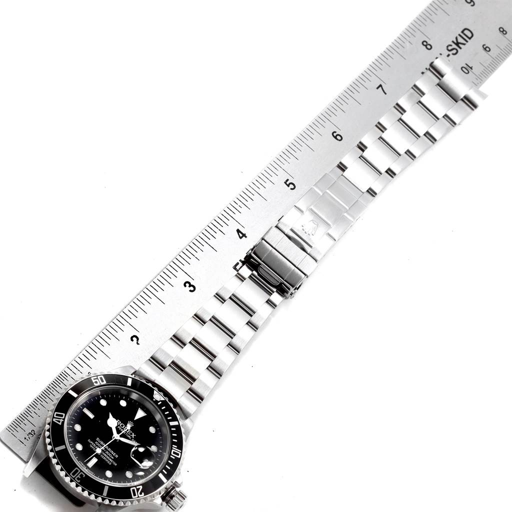 The image shows a Rolex Submariner 16610 Men's Stainless Steel Black Dial 16610 Men's Stainless Steel Black Dial watch laid out flat with a metal bracelet and clasp, alongside a ruler for measurement.
