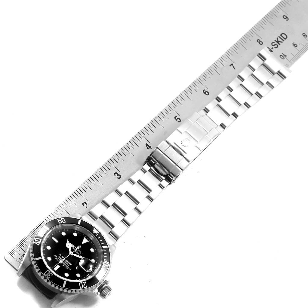 The image shows a top view of a Rolex Submariner 16610 Men's Stainless Steel Black Dial 16610 Men's Stainless Steel Black Dial watch, including its bracelet and clasp, alongside a ruler for measurement.