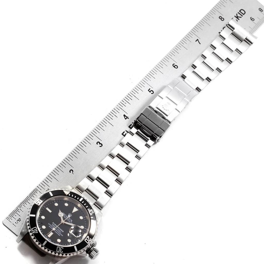 This image shows a top-down view of a Rolex Submariner 16610 Men's Stainless Steel Black Dial 16610 Men's Stainless Steel Black Dial watch and bracelet with a ruler beside it for scale.