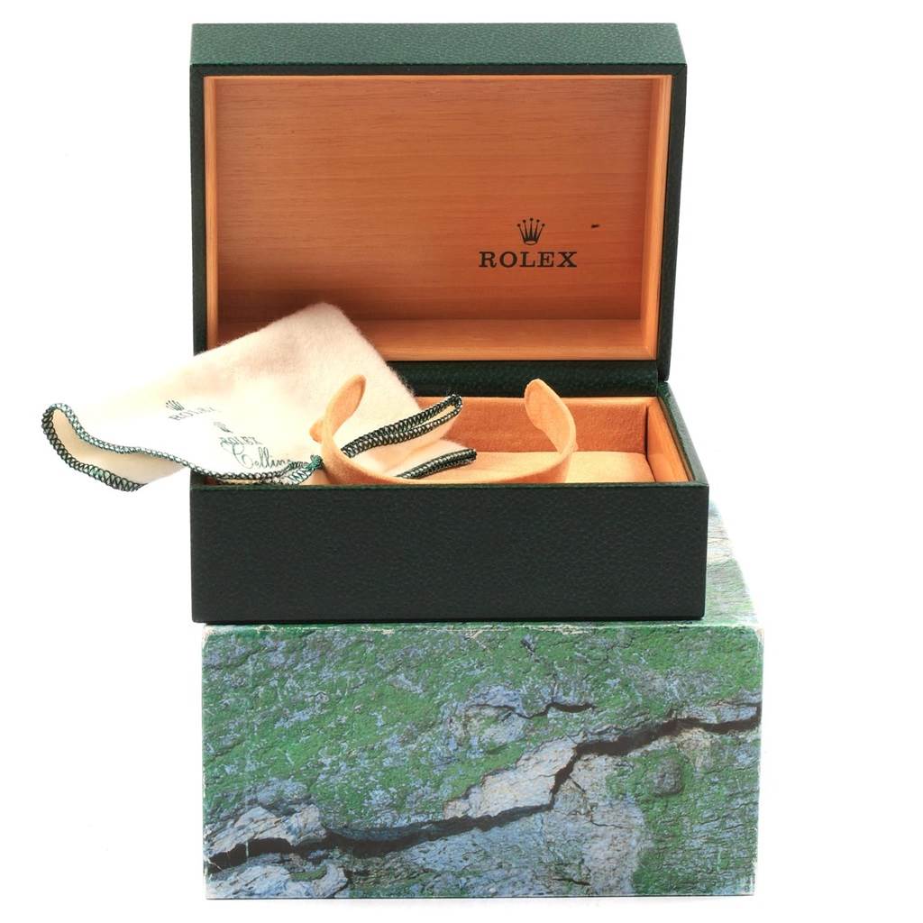 The image shows an open Rolex Submariner 16610 Men's Stainless Steel Black Dial 16610 Men's Stainless Steel Black Dial watch box with an inner cushion and a cleaning cloth.