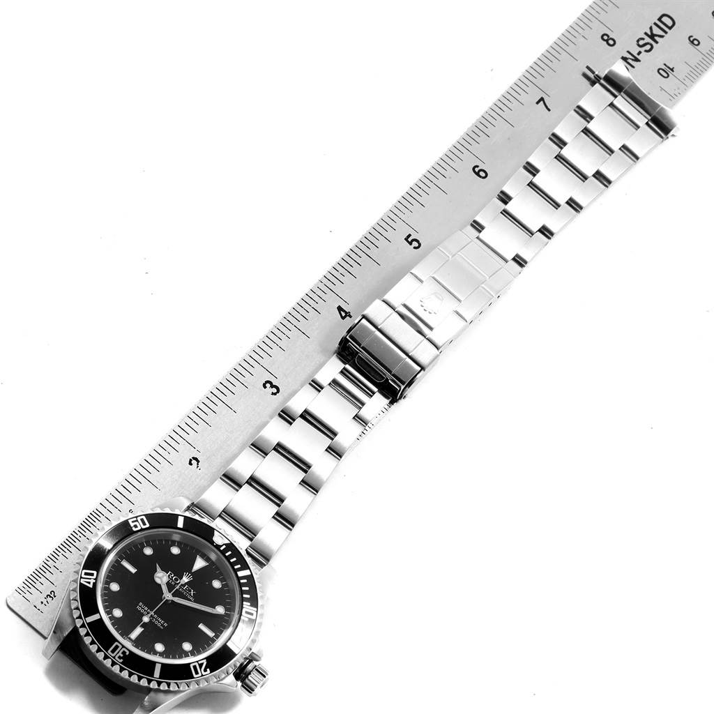 This image shows the Rolex Submariner 14060 Men's Stainless Steel Black Dial 14060 Men's Stainless Steel Black Dial watch laid flat next to a ruler, highlighting the watch face and metal bracelet.