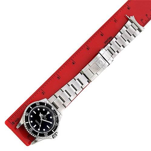 The image shows a Rolex Submariner 14060 Men's Stainless Steel Black Dial 14060 Men's Stainless Steel Black Dial watch laid flat, displaying its black dial, bezel, and metal bracelet next to a red ruler.