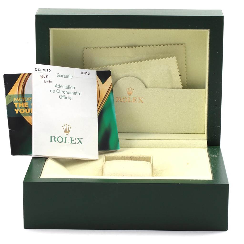 This image shows the opened box of a Rolex Submariner 16613 Men's Steel and Gold (two tone) Black Dial 16613 Men's Steel and Gold (two tone) Black Dial, displaying documentation and a polishing cloth inside.