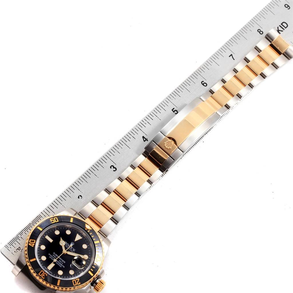 The image shows the Rolex Submariner 116613 Men's Steel and Gold (two tone) Black Dial 116613 Men's Steel and Gold (two tone) Black Dial watch face and bracelet laid next to a ruler for measurement.