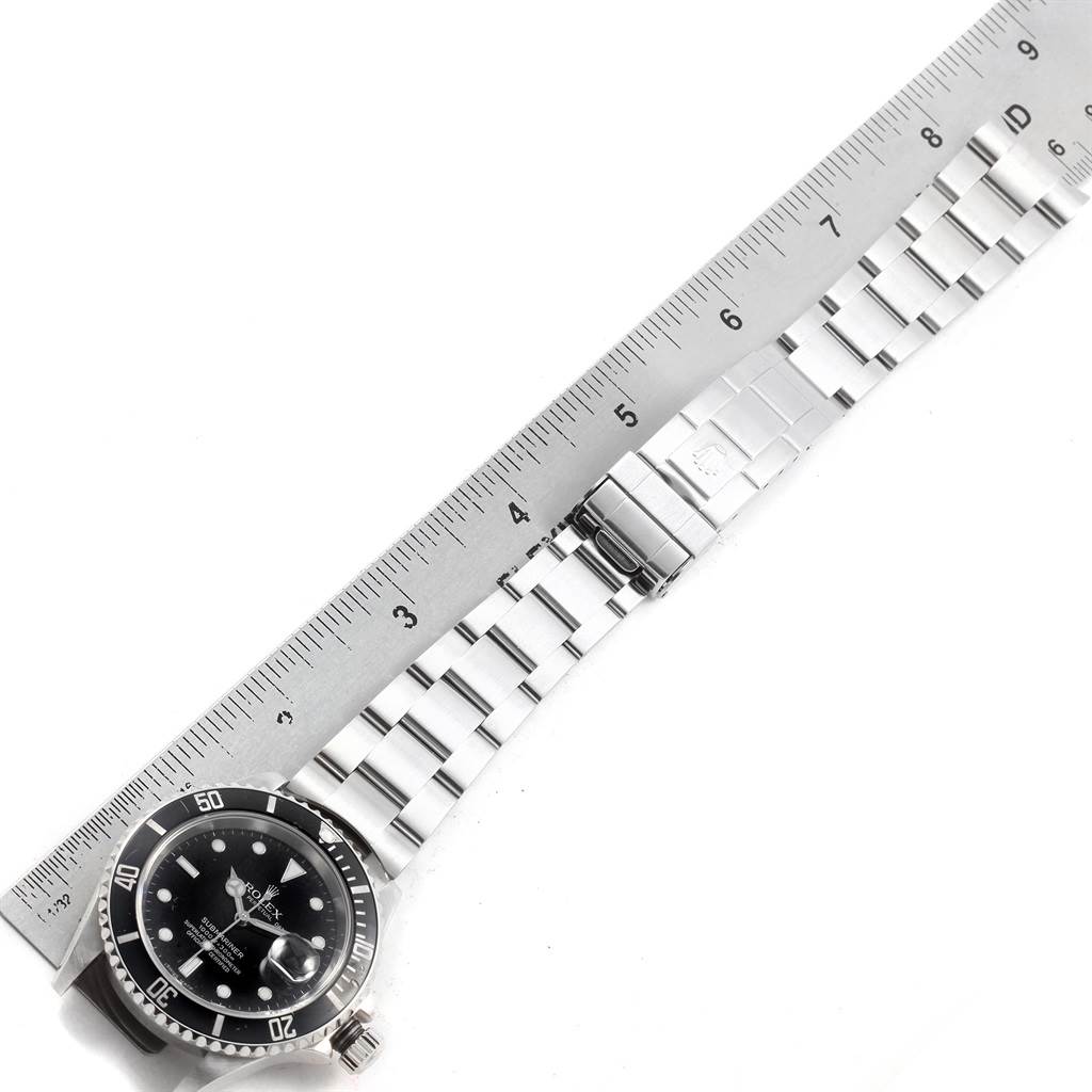 This image shows a top view of the Rolex Submariner 16610 Men's Stainless Steel Black Dial 16610 Men's Stainless Steel Black Dial watch, including its face, bezel, and bracelet placed next to a ruler for scale.