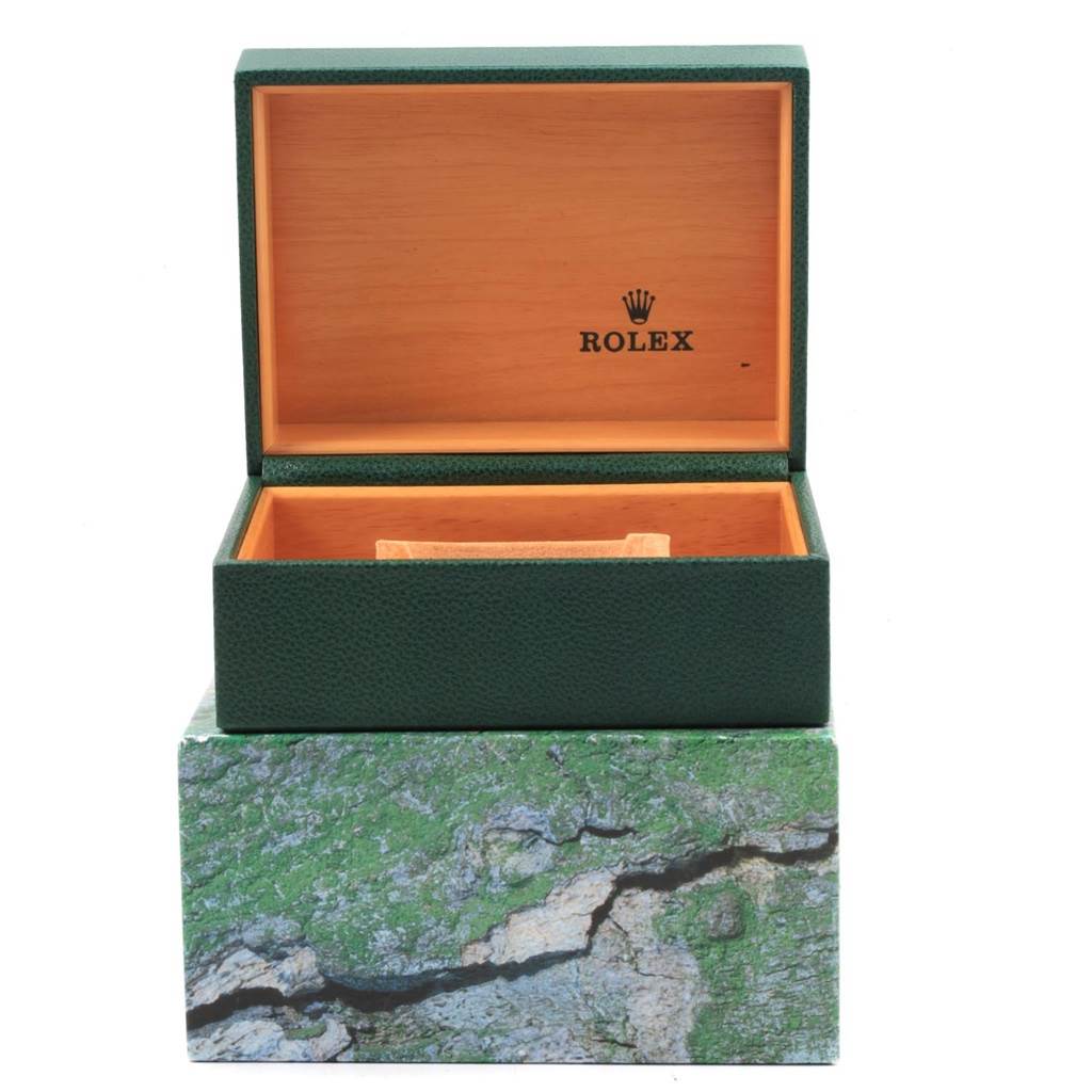 The image shows an empty Rolex watch box for the Submariner model, with its lid open, revealing a wood-textured interior.