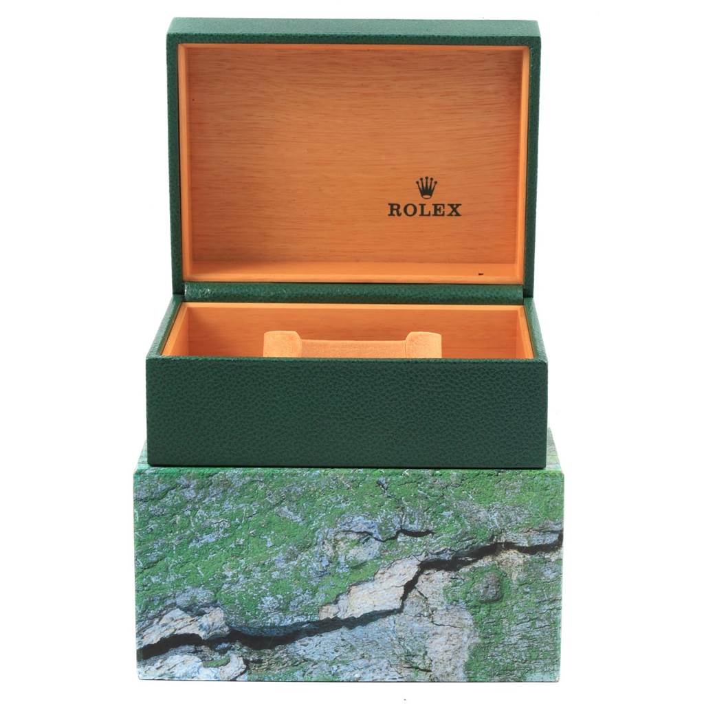The image shows an open Rolex watch box for the Submariner model, featuring a green exterior and wooden interior.