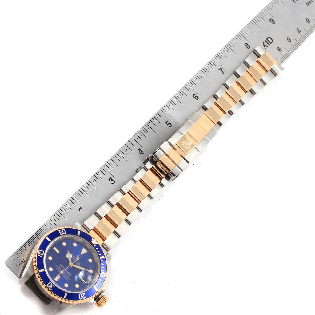 The image shows a top-down view of a Rolex Submariner 16613 Men's Steel and Gold (two tone) Blue Dial 16613 Men's Steel and Gold (two tone) Blue Dial watch, highlighting the dial, bezel, and bracelet next to a ruler for scale.