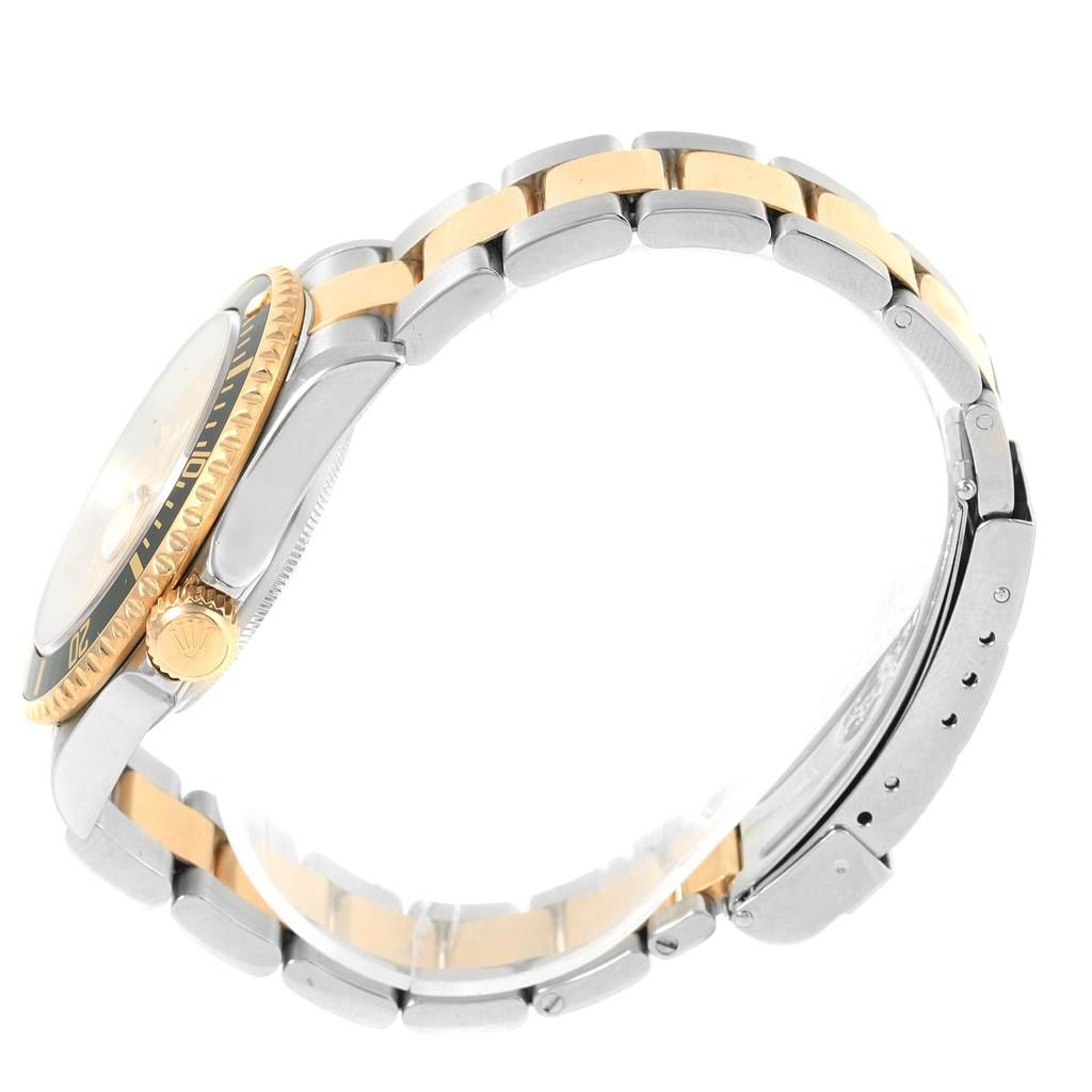 The Rolex Submariner 16613 Men's Steel and Gold (two tone) Champagne Dial 16613 Men's Steel and Gold (two tone) Champagne Dial watch is shown at a side angle, highlighting its two-tone bracelet, bezel, and crown.