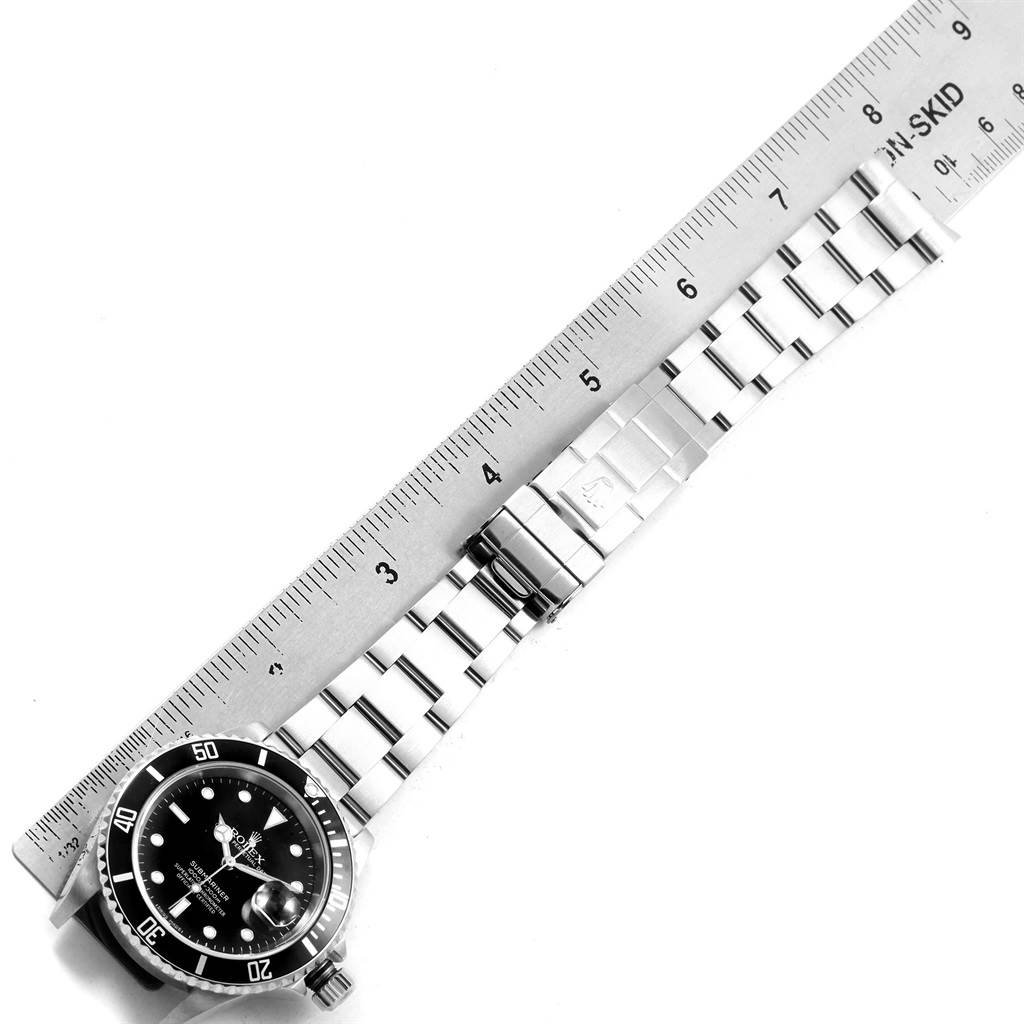 The image shows a top view of a Rolex Submariner 16610 Men's Stainless Steel Black Dial 16610 Men's Stainless Steel Black Dial watch with its stainless steel bracelet and a ruler for measurement.