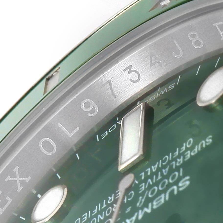 The image shows a close-up of the Rolex Submariner 116610LV Men
s Stainless Steel Green Dial 116610LV Men
s Stainless Steel Green Dial watch dial and rehaut with a partial view of the bezel and serial number engraving.