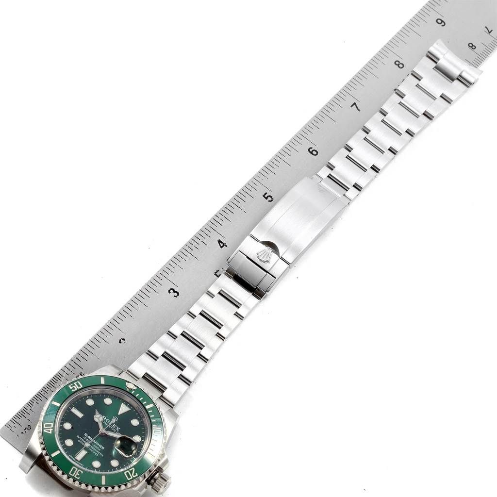 The image shows a Rolex Submariner 116610LV Men
s Stainless Steel Green Dial 116610LV Men
s Stainless Steel Green Dial watch with a green bezel, displayed alongside a metal ruler.
