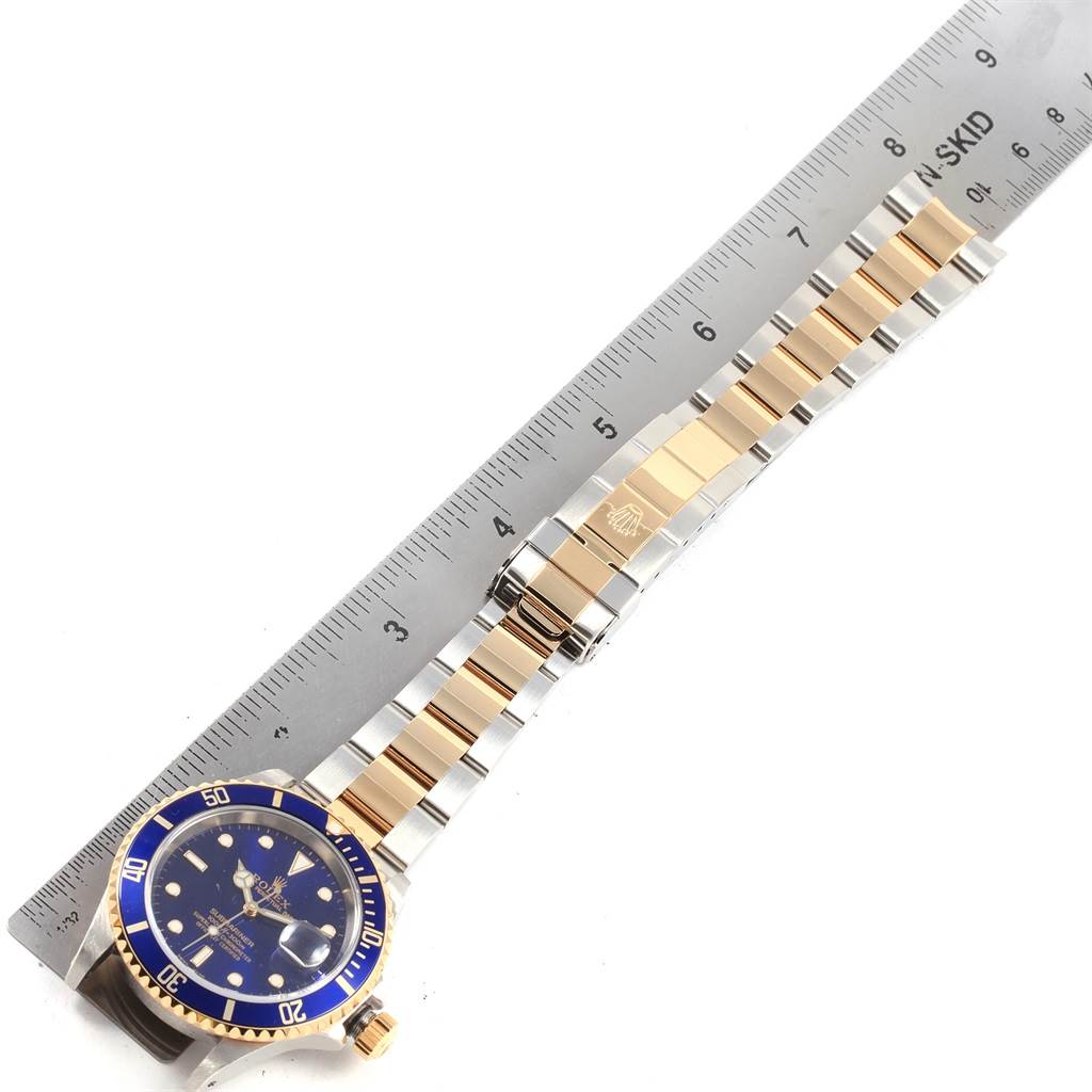 The image shows a top-down view of a Rolex Submariner 16613 Men's Steel and Gold (two tone) Blue Dial 16613 Men's Steel and Gold (two tone) Blue Dial watch, highlighting its blue dial, bezel, and two-tone metal bracelet.