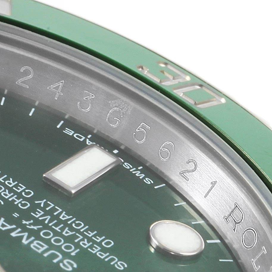 This close-up image of a Rolex Submariner 116610LV Men's Stainless Steel Green Dial 116610LV Men's Stainless Steel Green Dial watch shows part of the green bezel, the dial with text, and the edge of the crystal.