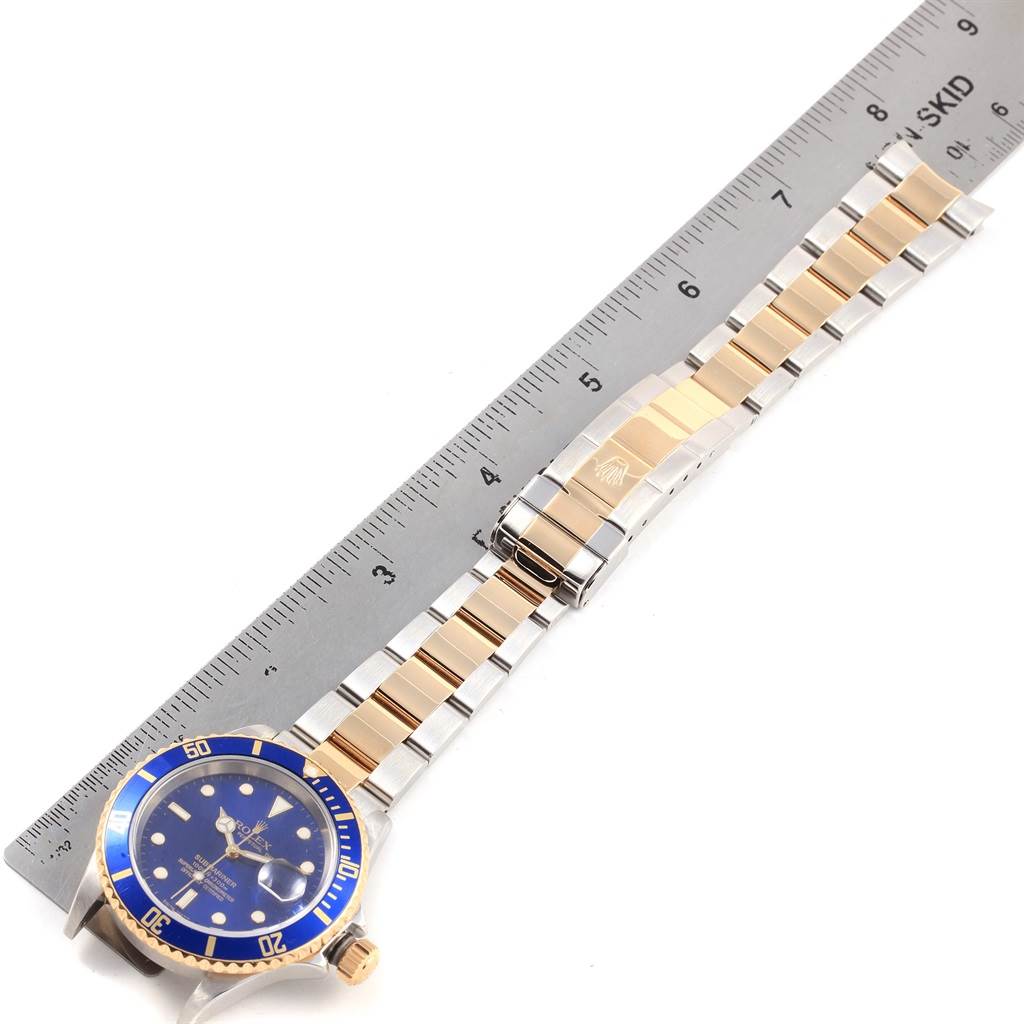 The image shows a Rolex Submariner 3 Men's Steel and Gold (two tone) Blue Dial 3 Men's Steel and Gold (two tone) Blue Dial watch laid flat with its bracelet next to a ruler for size reference.