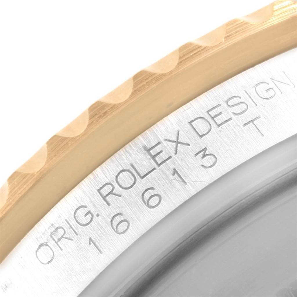 Close-up of the case edge and part of the bezel of a Rolex Submariner 16613 Men's Steel and Gold (two tone) Black Dial 16613 Men's Steel and Gold (two tone) Black Dial watch, showing engraved text and model number.