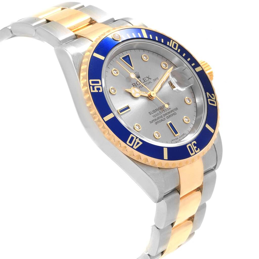 The image shows a Rolex Submariner 16613 Men's Steel and Gold (two tone) Grey Dial 16613 Men's Steel and Gold (two tone) Grey Dial watch from a slight side angle, highlighting its blue bezel, silver dial, and two-tone bracelet.