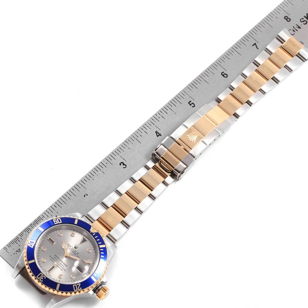 This image shows the Rolex Submariner 16613 Men's Steel and Gold (two tone) Grey Dial 16613 Men's Steel and Gold (two tone) Grey Dial watch laid flat next to a ruler, featuring the dial, bezel, and bracelet.
