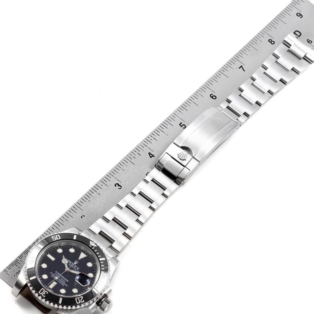 The Rolex Submariner 116610 Men's Stainless Steel Black Dial 116610 Men's Stainless Steel Black Dial watch is shown from an overhead angle, displaying its face, bezel, bracelet, and clasp alongside a ruler.