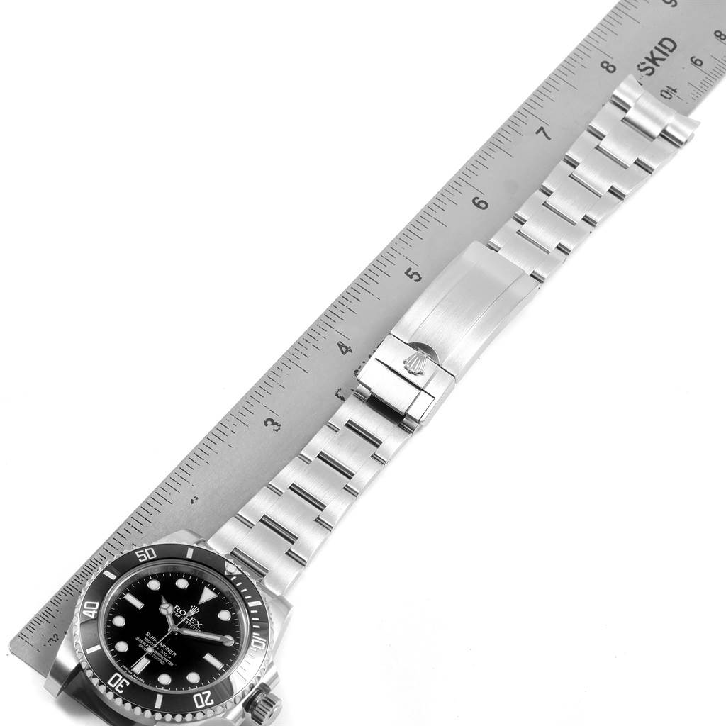The image shows the Rolex Submariner 114060 Men's Stainless Steel Black Dial 114060 Men's Stainless Steel Black Dial watch and metal bracelet laid next to a ruler for scale, with the dial facing up.