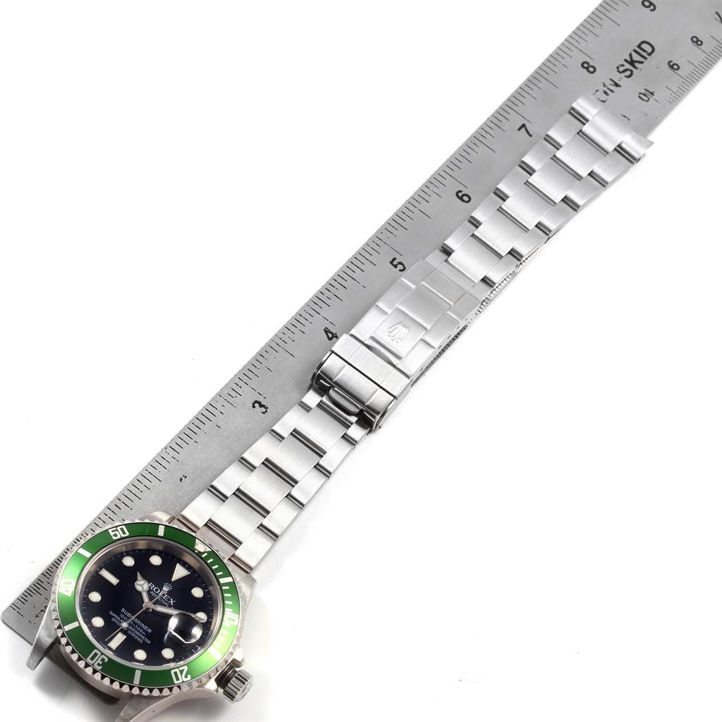 The image shows a Rolex Submariner 16610LV Men
s Stainless Steel Black Dial 16610LV Men
s Stainless Steel Black Dial watch with its stainless steel bracelet and clasp fully extended next to a ruler.