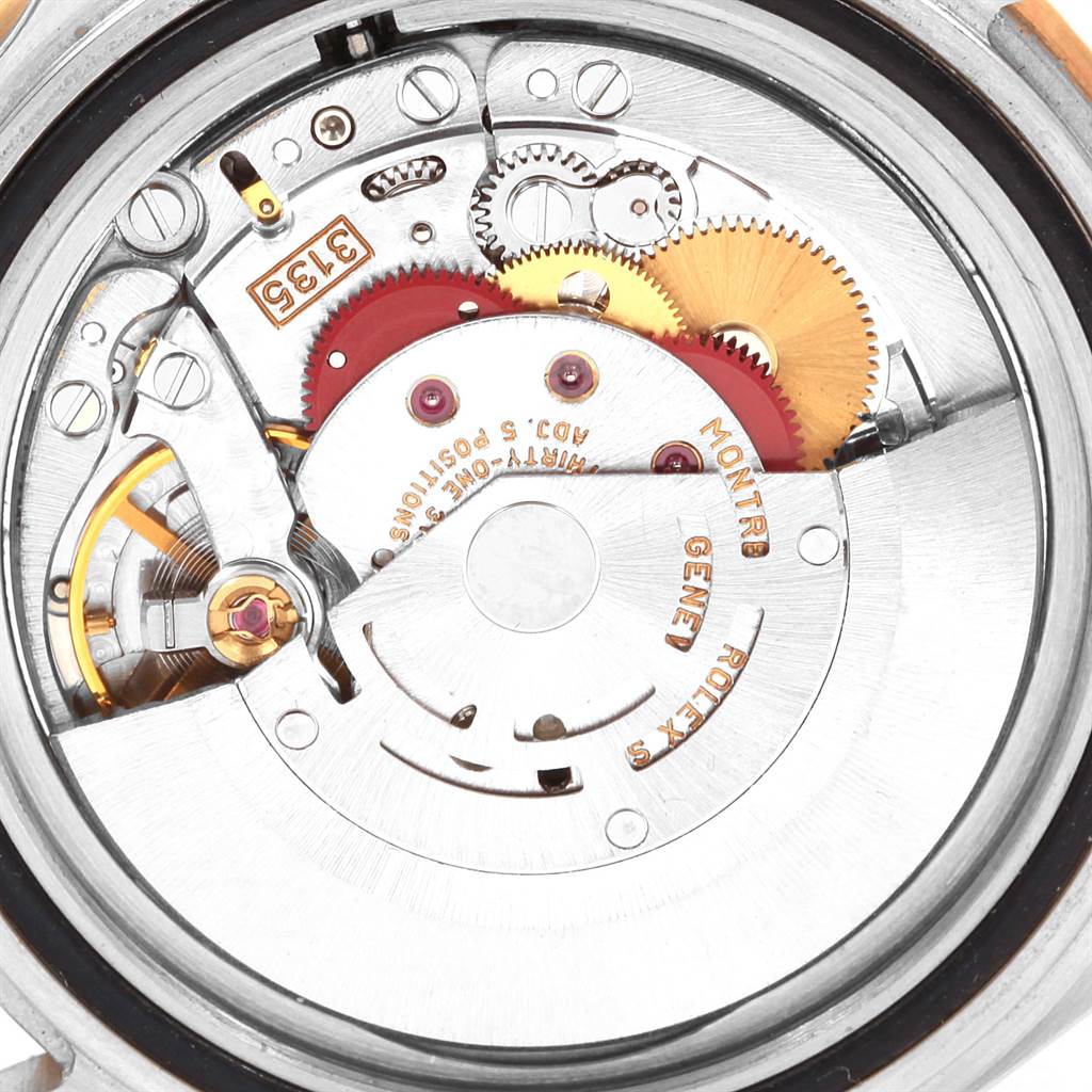 The image shows a close-up of the internal mechanism of a Rolex Submariner 16613 Men's Steel and Gold (two tone) Black Dial 16613 Men's Steel and Gold (two tone) Black Dial watch, highlighting the gears and movement components.