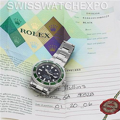 The image shows a Rolex Submariner 16610V Men's Stainless Steel Black Dial 16610V Men's Stainless Steel Black Dial watch placed on its certificate and documents, viewed from a top-down angle.