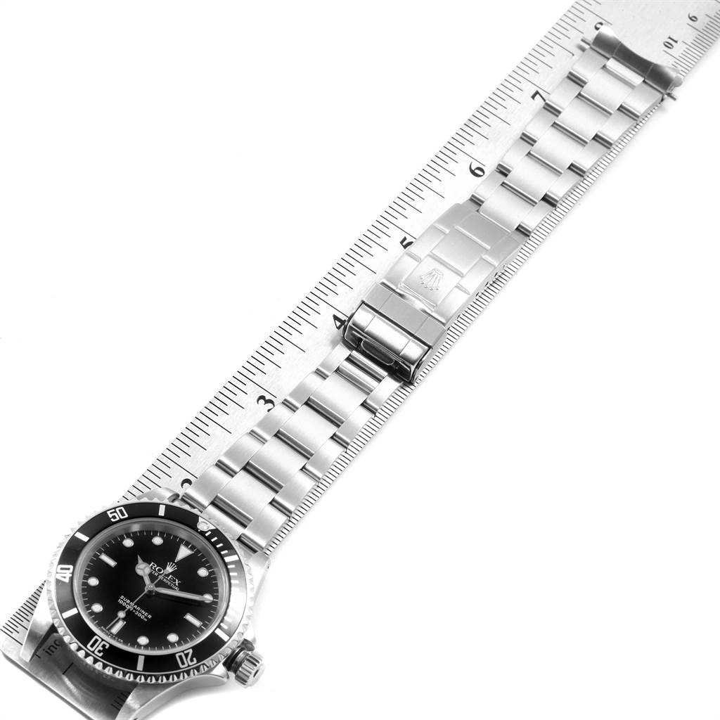 The image shows a top-down view of a Rolex Submariner 14060 Men's Stainless Steel Black Dial 14060 Men's Stainless Steel Black Dial watch, including its face, bezel, and stainless steel bracelet laid next to a ruler.