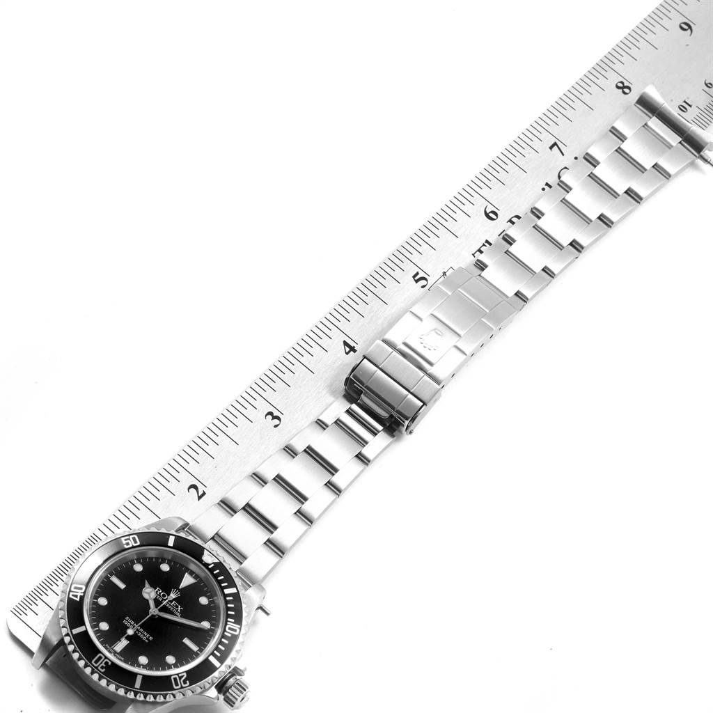 The image shows a Rolex Submariner 14060 Men's Stainless Steel Black Dial 14060 Men's Stainless Steel Black Dial watch at an oblique angle, displaying its dial, bezel, bracelet, and clasp next to a ruler.