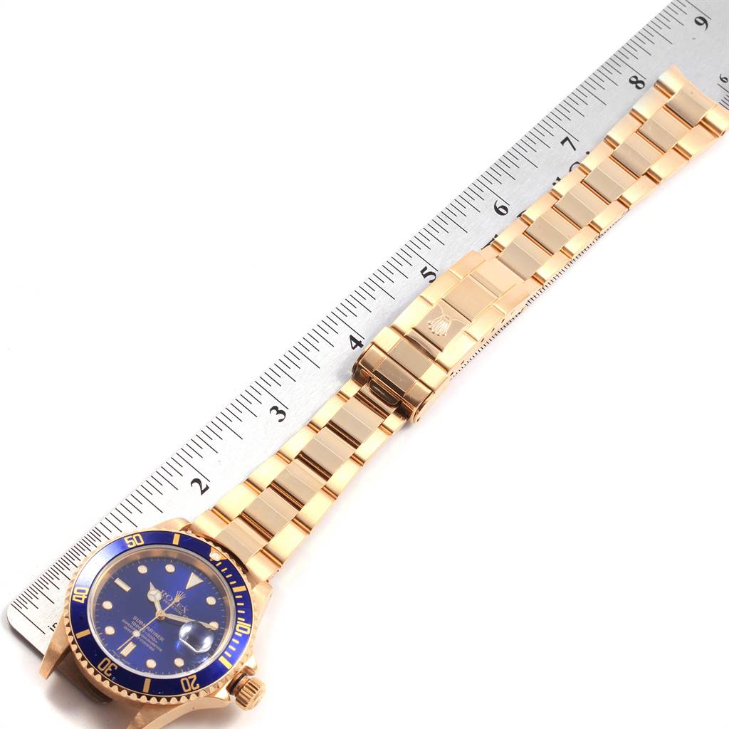 The image shows the full length of a Rolex Submariner 16618 Men's Yellow Gold Blue Dial 16618 Men's Yellow Gold Blue Dial watch laid flat next to a ruler for size reference.