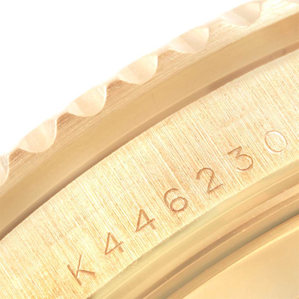 This macro shot focuses on the Submariner by Rolex, highlighting its engraved serial number and the edge of the bezel.