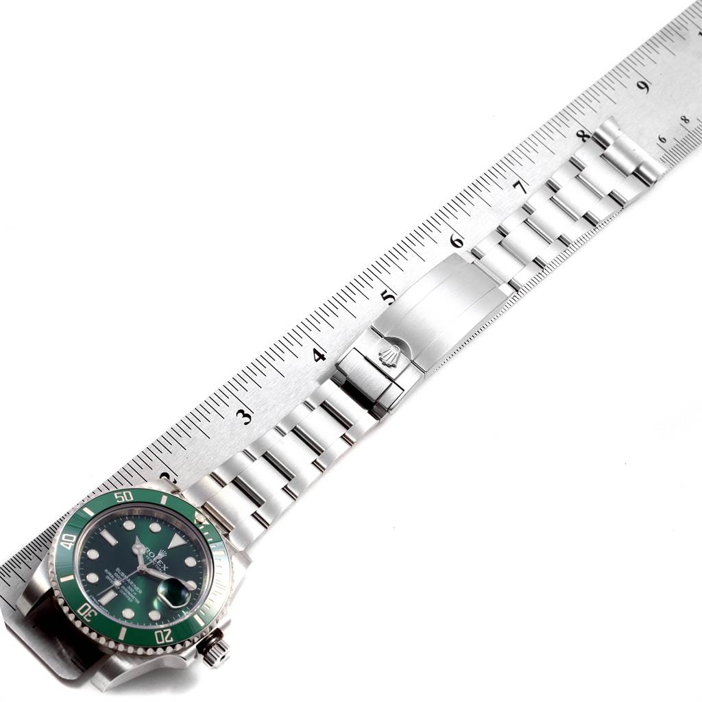 The image shows a Rolex Submariner 116610LV Men's Stainless Steel Green Dial 116610LV Men's Stainless Steel Green Dial watch horizontally with its face and full bracelet extended against a measuring scale.