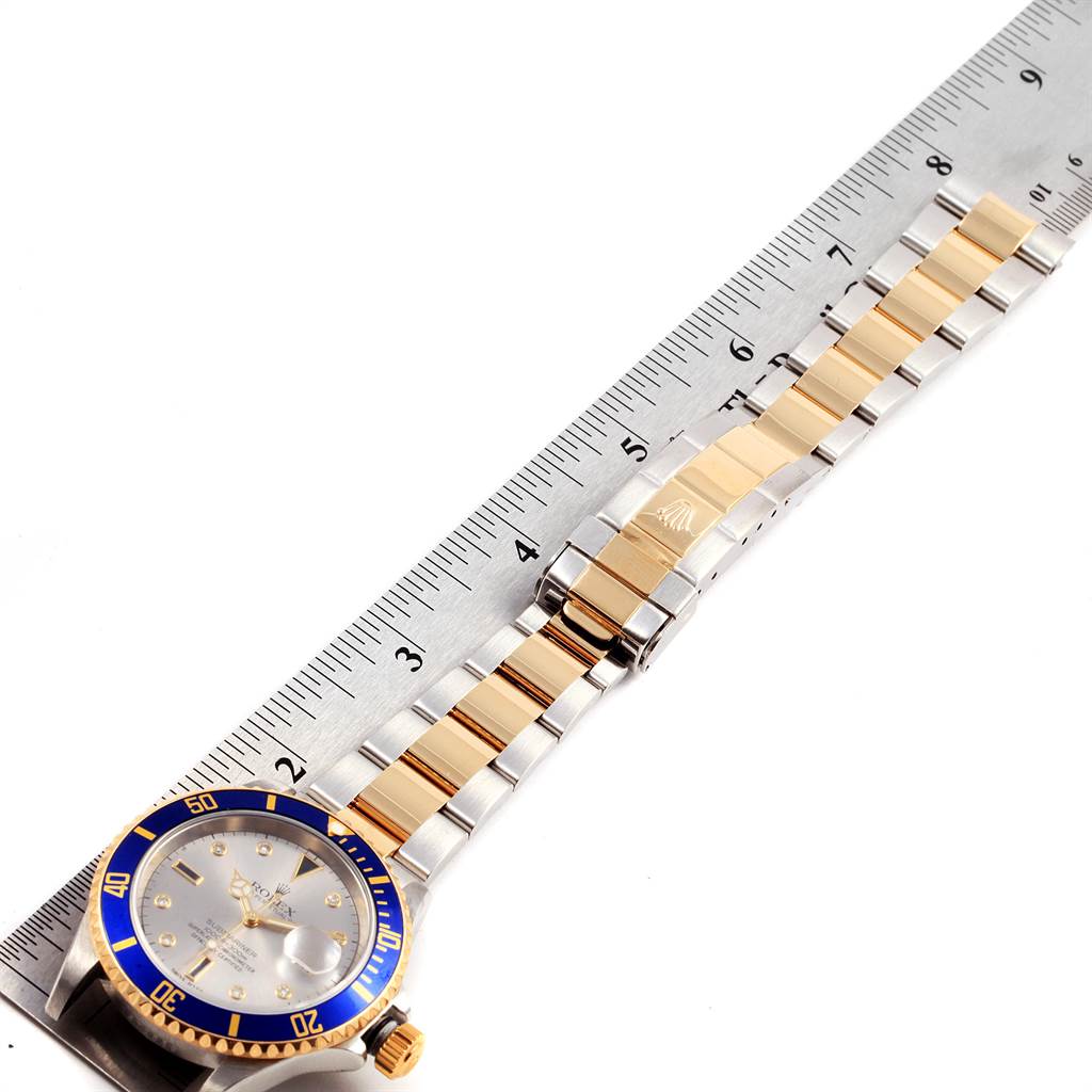 The image shows a Rolex Submariner 16613 Men's Steel and Gold (two tone) Grey Dial 16613 Men's Steel and Gold (two tone) Grey Dial watch laid flat, highlighting the face, bezel, and metal bracelet next to a measuring ruler.