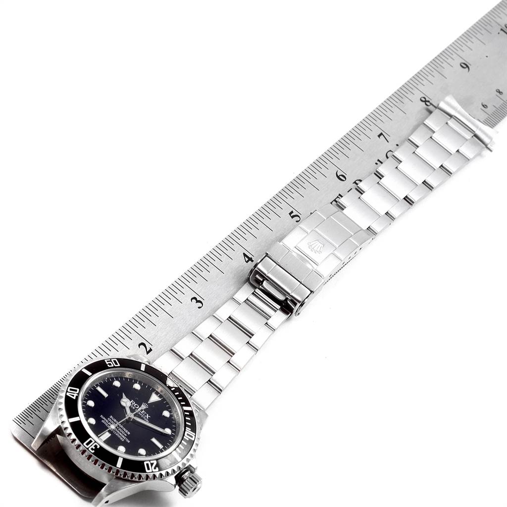 The image shows a Rolex Submariner 14060 Men's Stainless Steel Black Dial 14060 Men's Stainless Steel Black Dial watch lying flat, with the face and entire metal bracelet visible alongside a ruler for scale.