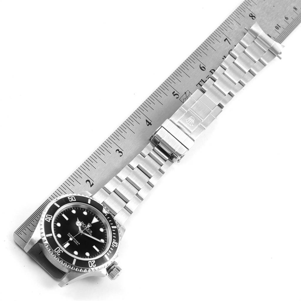 The image shows a top-down view of a Rolex Submariner 14060 Men's Stainless Steel Black Dial 14060 Men's Stainless Steel Black Dial with its stainless steel bracelet fully extended beside a ruler.