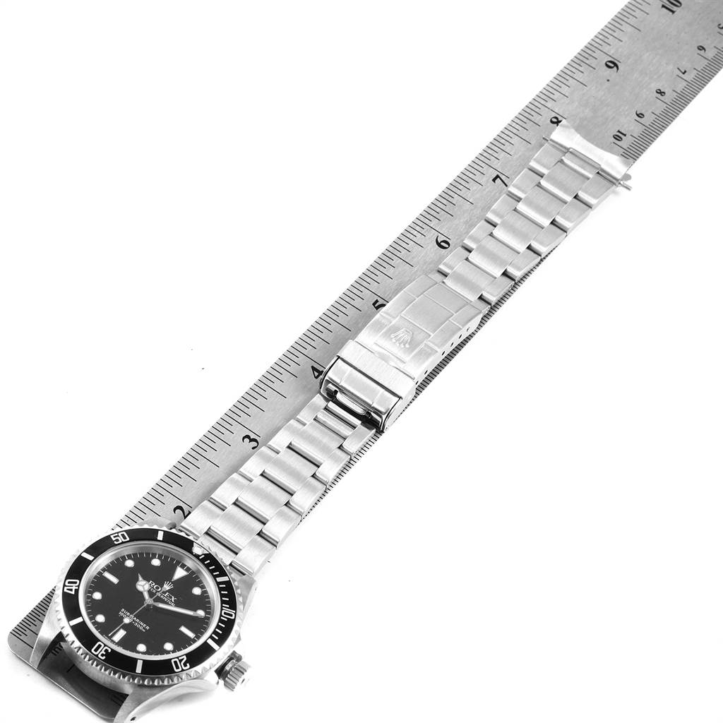 This is a top view of a Rolex Submariner 14060 Men's Stainless Steel Black Dial 14060 Men's Stainless Steel Black Dial, showing the entire watch including the face, bezel, crown, and bracelet clasp measured against a ruler.