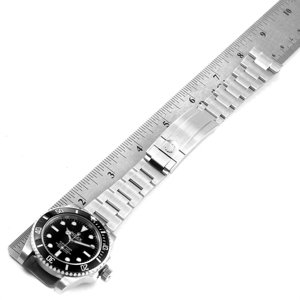 The image shows a Rolex Submariner 114060 Men
s Stainless Steel Black Dial 114060 Men
s Stainless Steel Black Dial watch laid flat on a measuring ruler, displaying the face, bracelet, and clasp.