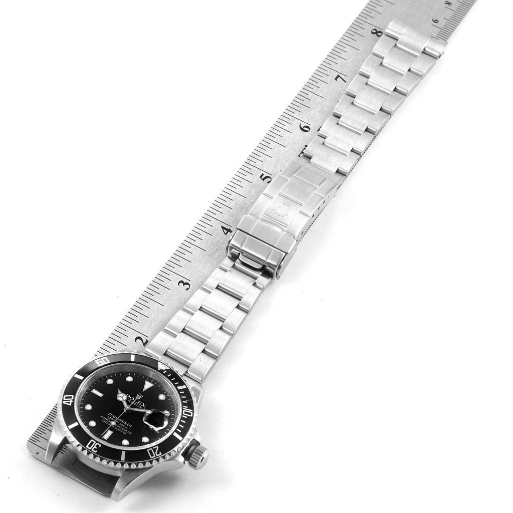 The image shows a Rolex Submariner 16610 Men's Stainless Steel Black Dial 16610 Men's Stainless Steel Black Dial watch laid flat, displaying the face, bezel, and bracelet against a ruler for scale.