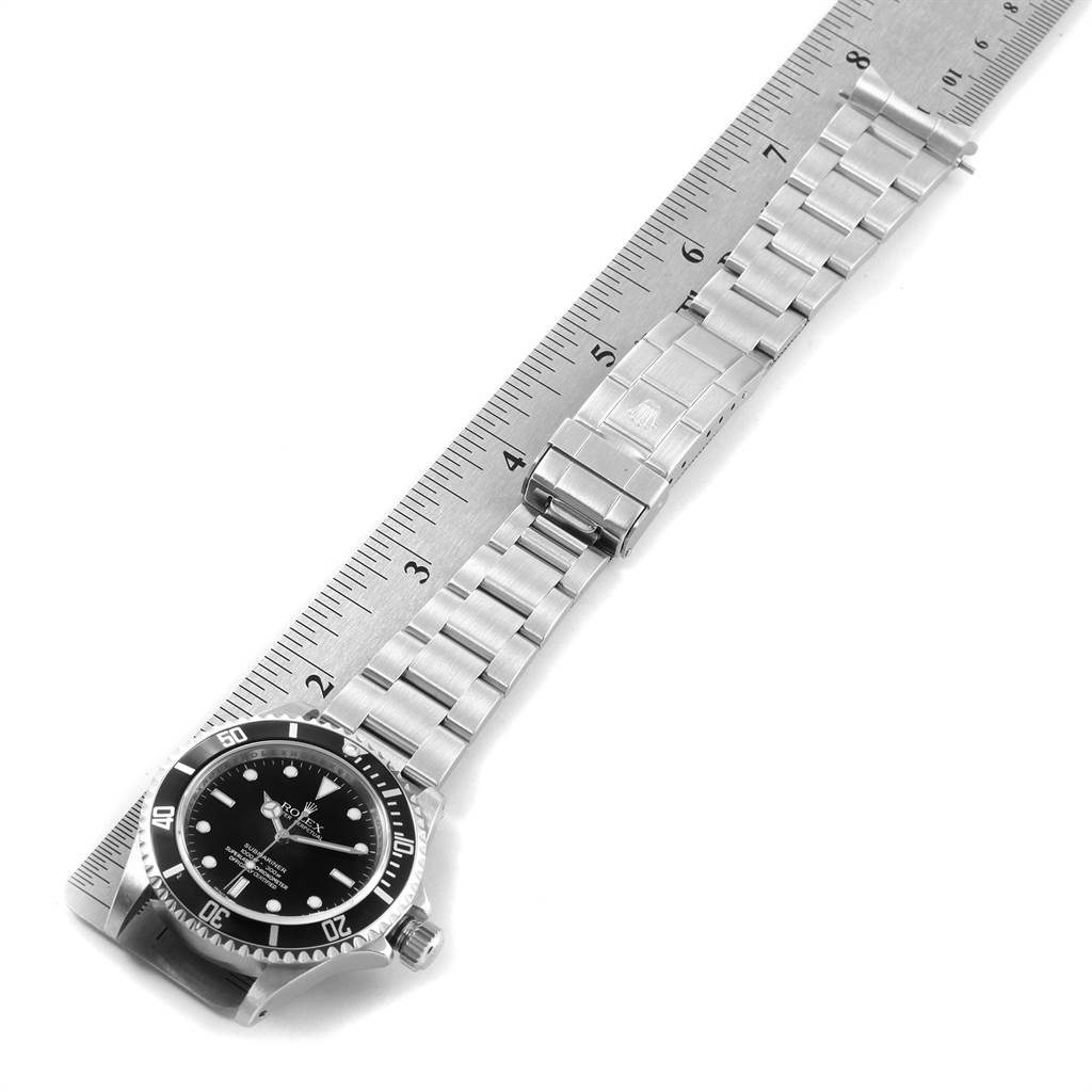 This image shows a Rolex Submariner 14060 Men's Stainless Steel Black Dial 14060 Men's Stainless Steel Black Dial watch laid flat on a ruler, displaying the watch face, bezel, and bracelet.