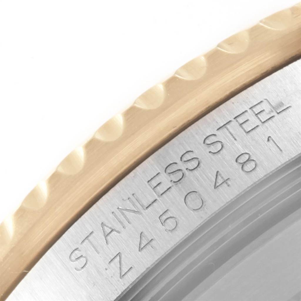 The image shows a close-up of the side of a Rolex Submariner 16613 Men's Steel and Gold (two tone) Grey Dial 16613 Men's Steel and Gold (two tone) Grey Dial watch, focusing on the stainless steel case with engraved serial number.
