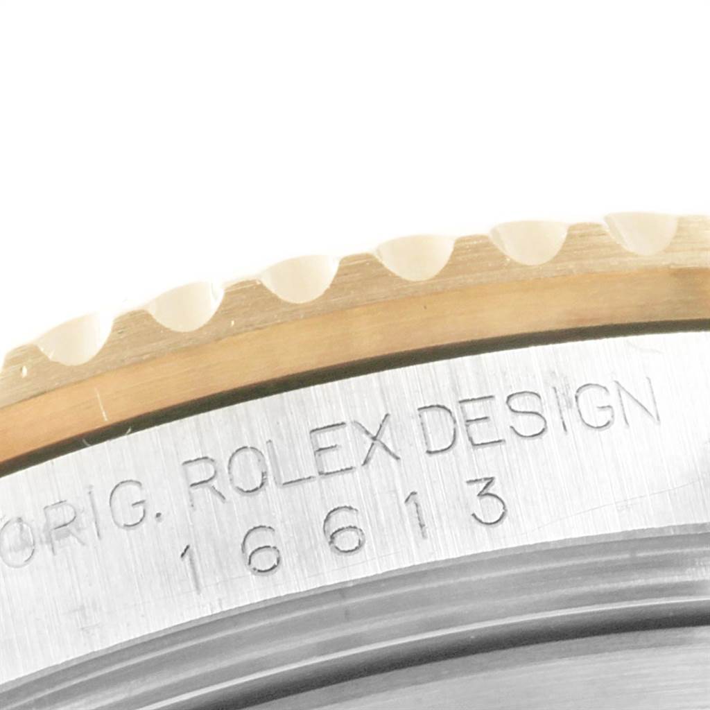 The image shows a close-up of the bezel and engraved case of a Rolex Submariner 16613 Men
s Steel and Gold (two tone) Champagne Dial 16613 Men
s Steel and Gold (two tone) Champagne Dial watch, model number 16613.